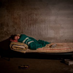 A girl who was brought to see a doctor is asleep in the basement of Novoazovsk ambulance station during the shelling
