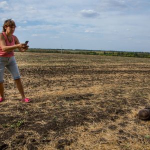 A local woman takes a picture of the dead Ukrainian soldier in the field near the town of Komsomolskoye, Donetsk region.