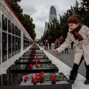 A girl lays flowers at the Alley of Martyrs memorial