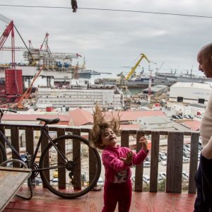 Janbulat Asperov watches his granddaughter play on the balcony of his house near the Bibi Heybet mosque.