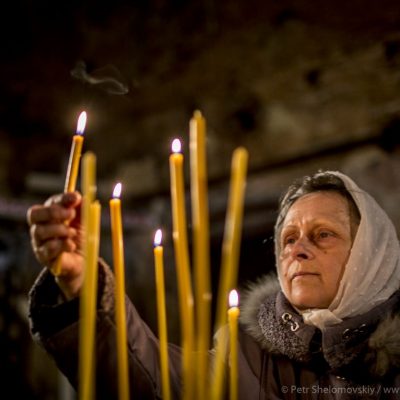 Female believer lighting candles during Easter mass in destroyed Orthodox church in Petrovskiy district of Donetsk