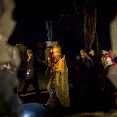 Priests and worshippers during the easter procession as seen through the broken glass window of destroyed church in Petrovskiy district of Donetsk